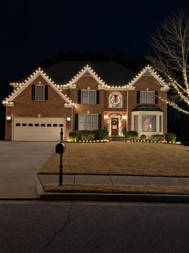 Warm white roofline lighting with an illuminated entry and wreath.