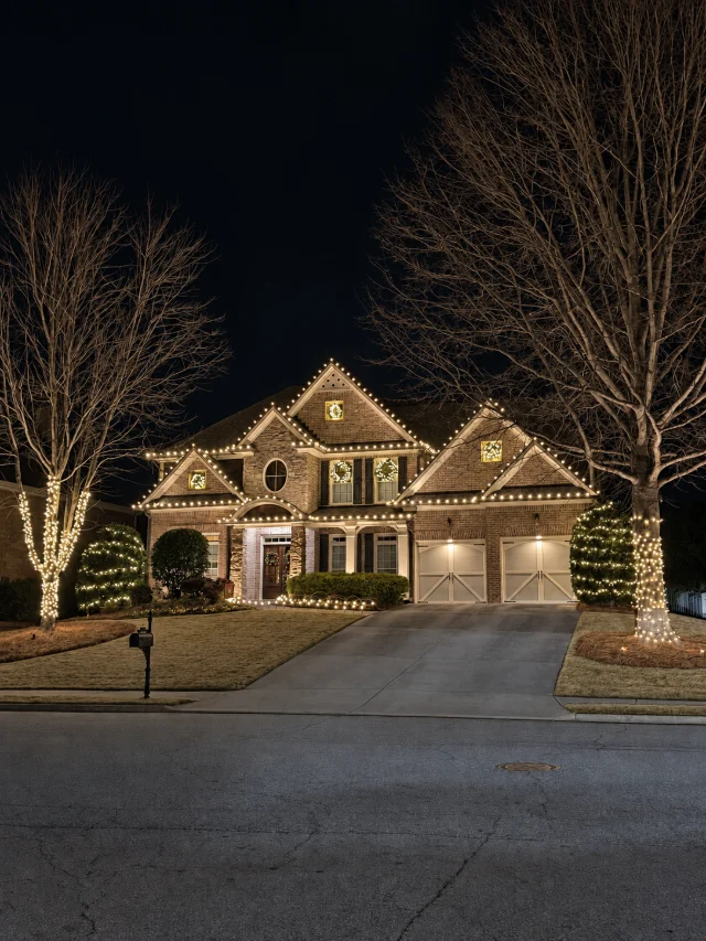 Warm white roofline lighting, tree wraps, and window wreaths.