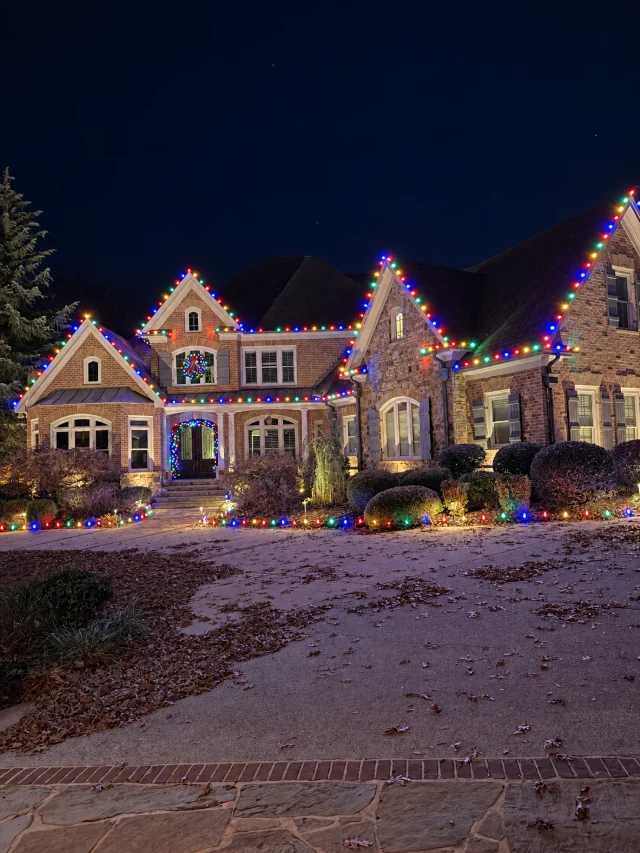 Multicolor roofline lighting with matching lights along the walkway and planting beds.