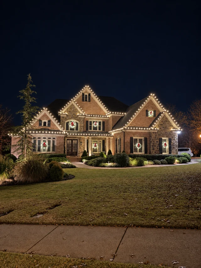 Warm white roofline lighting with illuminated window wreaths.