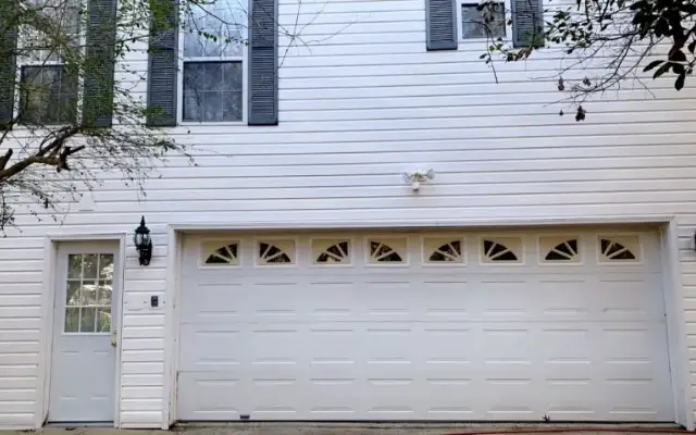 White two-story home and garage after washing with clean siding and a brighter garage door.