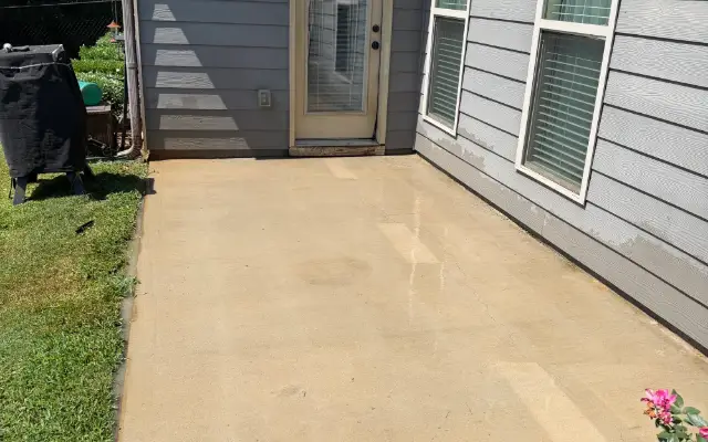 Clean concrete patio beside a gray house after pressure washing