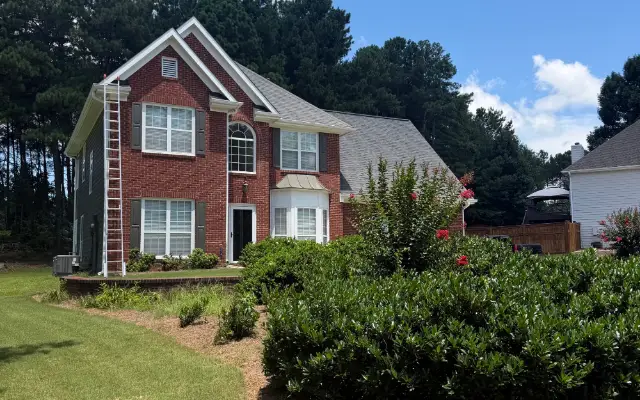 This is a photo of the front of a house with a ladder propped up on the side to reach the roof