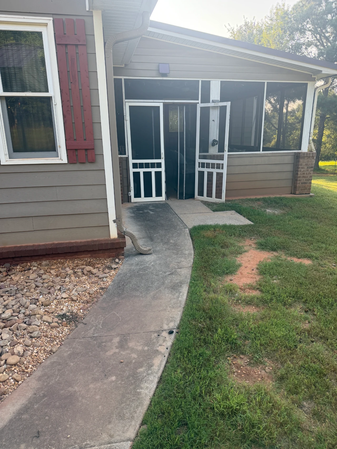 Curved concrete walkway leading to a screened back porch.