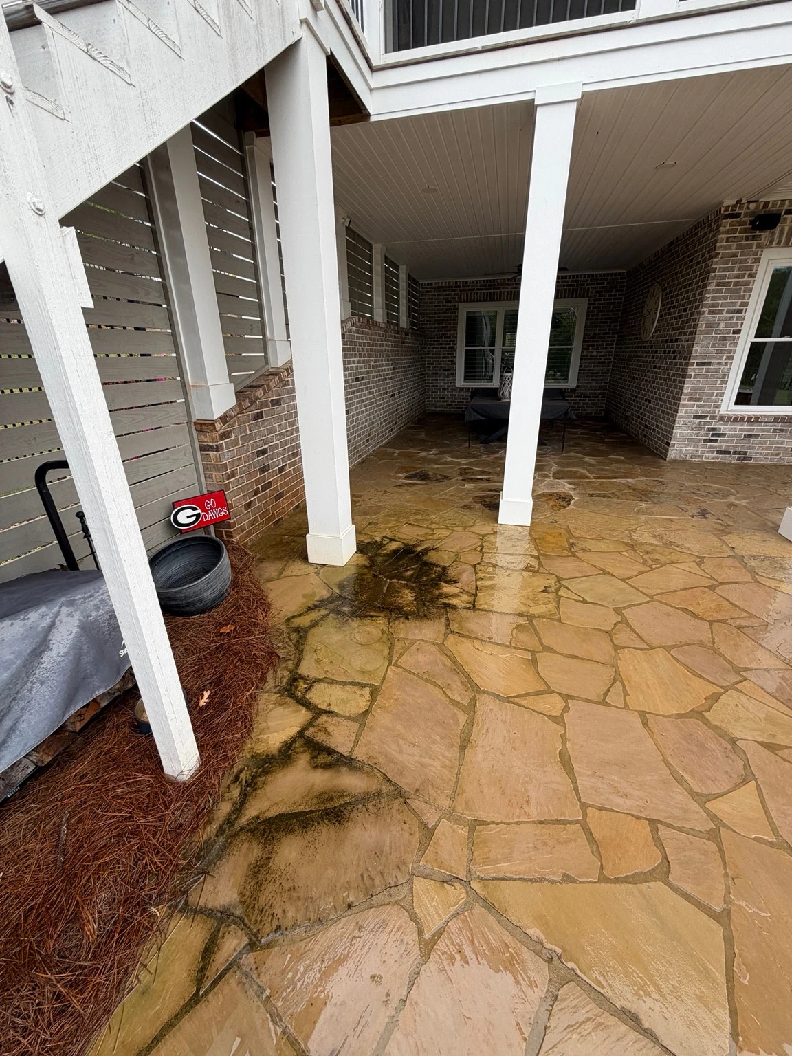 Covered flagstone patio in Statham with dark surface buildup before cleaning
