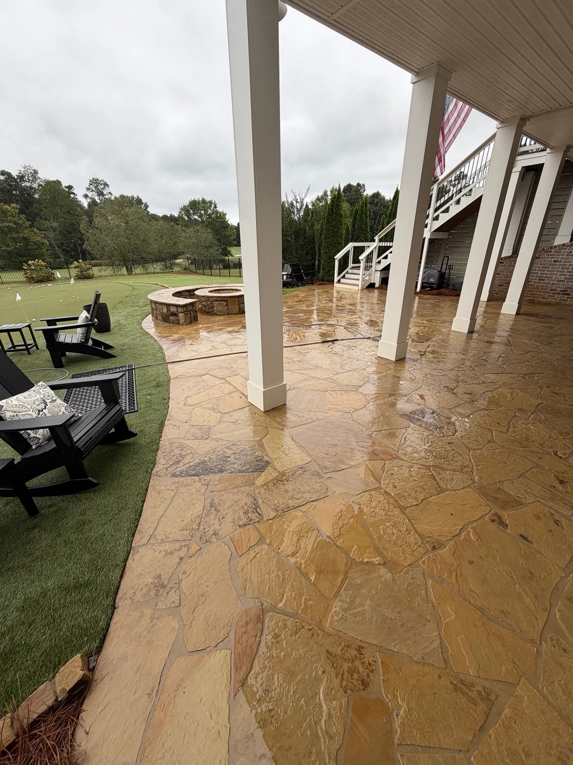 Cleaned flagstone beside an artificial turf putting green in Statham with the stone still wet