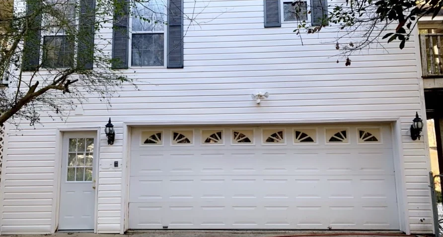 White two-story home and garage after washing with clean siding and a brighter garage door.