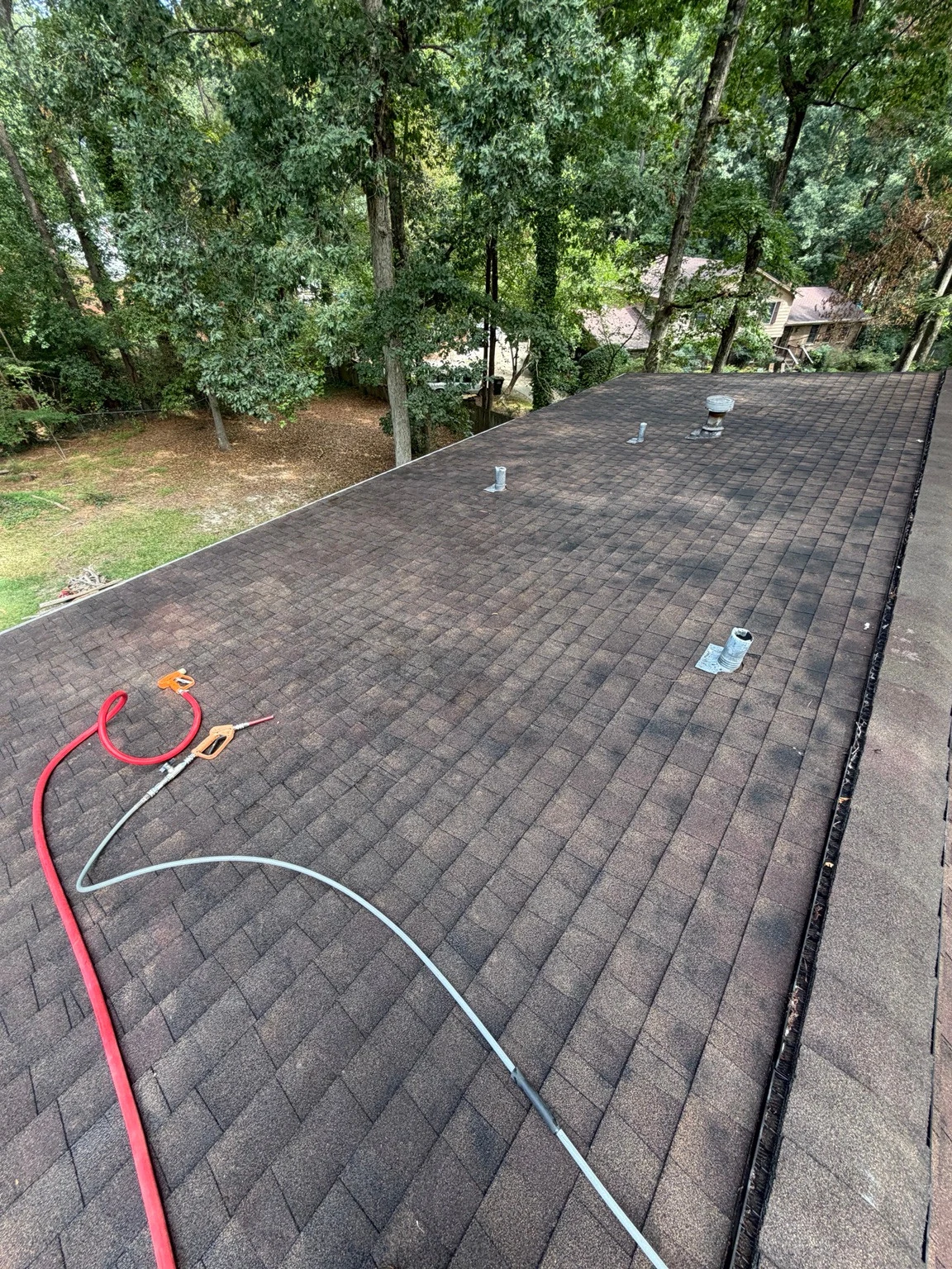 Shingle roof section with vents and dark streaking in Winder before washing