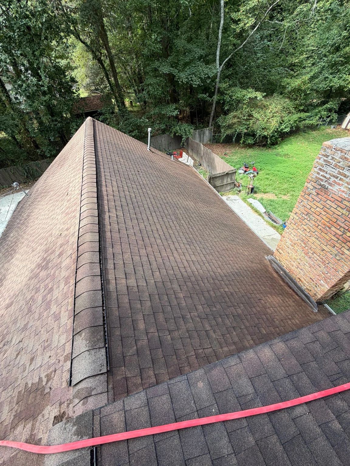 Shingle roof section beside a brick chimney in Winder before washing